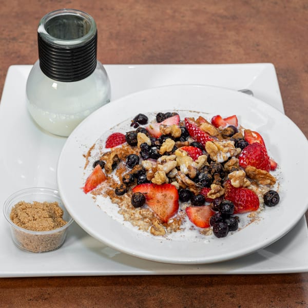 Ida's Cafe oatmeal with fresh strawberries, blueberries, walnuts, and a side of brown sugar.