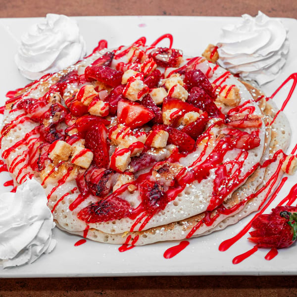 Fluffy pancakes topped with strawberries, syrup, powdered sugar, and whipped cream at Ida's Cafe.